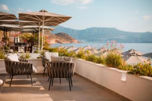 eine Terrasse mit Stühlen und Sonnenschirmen und dem Wasser in der Unterkunft Megisti Hotel in Megisti