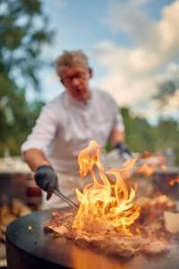 a man cooking food on a grill with fire at Château Salavaux in Salavaux