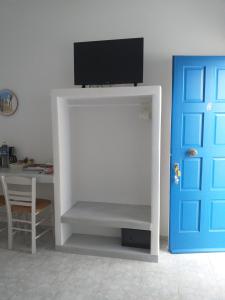 a tv on top of a white stand next to a door at Captain Stavros in Pollonia