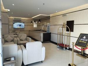 a living room with white chairs and a kitchen at Al Shark Park Serviced Apartment in Najran