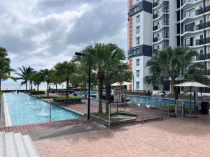 a swimming pool with palm trees next to a building at dipantai TIMURBAY SeaView GrdFloor Private Residence in Kuantan