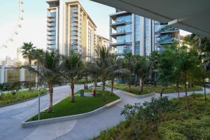 a park with palm trees in front of a building at Primestay - Astonishing 1BR in Bluewaters Island in Dubai