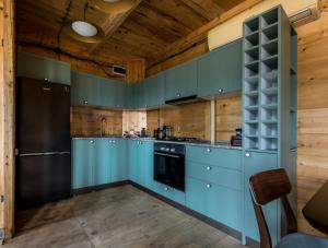 a kitchen with blue cabinets and a black refrigerator at Hill Inn in Keda