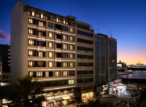 un edificio alto con luces encendidas en una ciudad en The Port Square Hotel, en Pireo