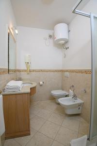 łazienka z 2 toaletami, umywalką i prysznicem w obiekcie Elbamar Marina Di Campo w mieście Marina di Campo