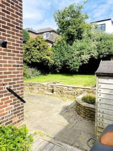 a backyard with a brick building and a stone wall at 3 BR Property in Prestwich 15 mins from Manchester City Centre Garden Free parking Superfast WIFI Netflix in Manchester