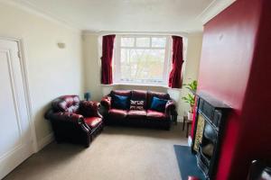 una sala de estar con 2 sillas de cuero y una ventana en 3 BR Property in Prestwich 15 mins from Manchester City Centre Garden Free parking Superfast WIFI Netflix en Mánchester