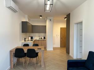 kuchnia i salon z drewnianym stołem i krzesłami w obiekcie Apartament Metropolis 15 w Toruniu