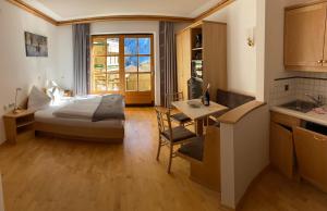 a bedroom with a bed and a table and a kitchen at Landhaus Rosengartl Krimml in Oberkrimml