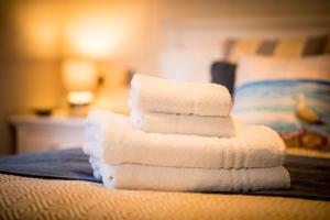 einen Stapel Handtücher auf dem Bett in der Unterkunft St Tinney Farm Cornish Cottages & Lodges, a tranquil base only 10 minutes from the beach in Otterham