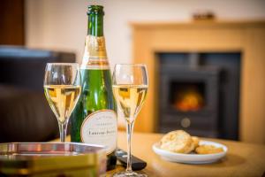 twee glazen witte wijn naast een fles champagne bij St Tinney Farm Cornish Cottages & Lodges, a tranquil base only 10 minutes from the beach in Otterham