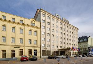 Imperial Hotel Ostrava في أوسترافا: مبنى كبير به سيارات تقف في موقف للسيارات