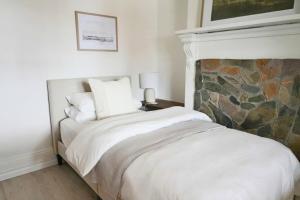 a bedroom with a white bed with a stone fireplace at The Modern Victorian 200 metres from CBD in Bathurst