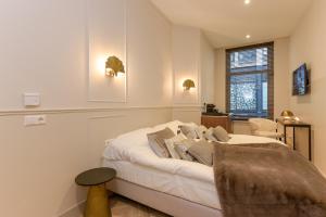 a white bedroom with a bed and a chair at Novallure City Centre in The Hague