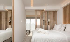 sypialnia z 2 łóżkami z białą pościelą i lustrem w obiekcie LUX&EASY Acropolis Suites w Atenach