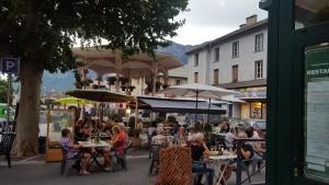 un groupe de personnes assis à des tables à l'extérieur d'un bâtiment dans l'établissement Hôtel Restaurant Glaizette, à LʼArgentière-la-Bessée