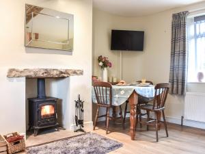 a living room with a table and a fireplace at High Dale Cottage in Bellerby