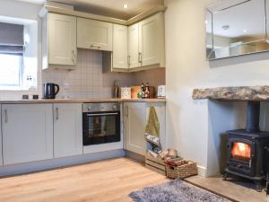 a kitchen with white cabinets and a stove at High Dale Cottage in Bellerby