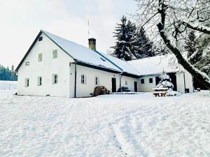 a white house with snow on the ground in front of it at Romantická chalupa s krbem in Hořice na Šumavě