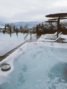 a jacuzzi tub with an umbrella and chairs in the snow at Royal Valentina Castle in Ognyanovo