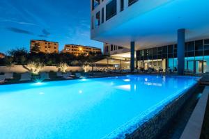 a swimming pool in front of a building at night at Hotel Salona Palace in Solin