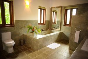 a large bathroom with a tub and a toilet at Kingfisher Bamboo Garden Villa in Unawatuna
