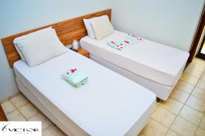two beds in a room with white sheets at Hotel Victor in Patos de Minas