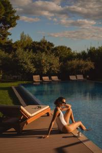 une femme en robe blanche assise à côté d'une piscine dans l'établissement Hotel Salona Palace, à Solin