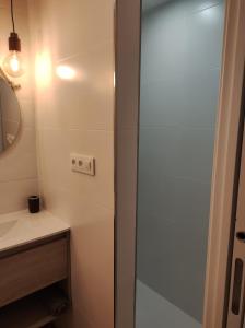 Un baño con una puerta de ducha de cristal junto a un lavabo. en Natipao, en Rota