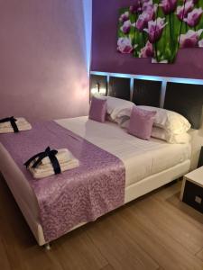 1 dormitorio con 1 cama grande y pared morada en Albis Rooms Guest House en Fiumicino