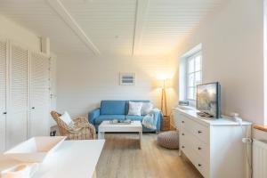 a living room with a blue couch and a tv at Seestern in Vollerwiek