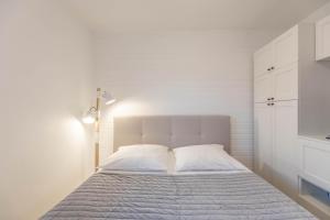 a white bedroom with a bed with white cabinets at Seestern in Vollerwiek