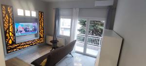 a living room with a tv and two windows at Joanna in Katerini