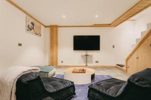 a living room with two chairs and a flat screen tv at Chalet Isabella : cozy & comfy in central Chamonix in Chamonix-Mont-Blanc