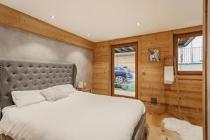 Chalet Isabella : cozy & comfy in central Chamonix في شامونيه مون بلان: غرفة نوم بسرير كبير وجدران خشبية