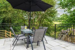 a table and chairs with an umbrella on a patio at Bryntirion Lodge in Y Felinheli