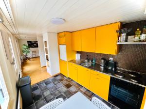 cocina con armarios amarillos, mesa y sillas en Newly furnished beautiful old building apartment in the center with Apple TV O1, en St. Gallen