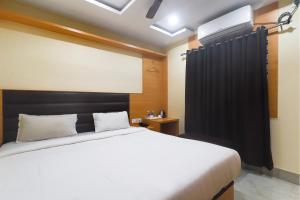 a bedroom with a white bed and a black curtain at FabExpress Ganpati 2 in Siliguri