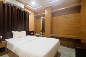 a bedroom with a white bed and a window at FabExpress Ganpati 2 in Siliguri