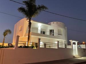 uma casa branca com uma palmeira em frente em Villa à 2 pas de la plage - 4 chambres em Imsouane