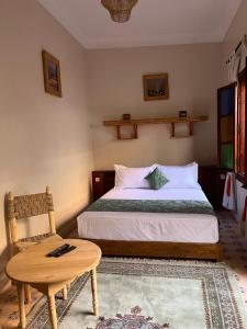 a bedroom with a bed and a table and a chair at Riad Dar Les Freres in Marrakech