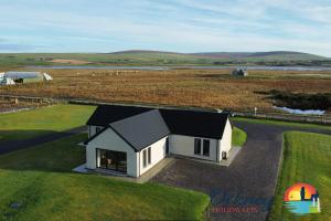 une petite maison blanche avec un toit noir dans un champ dans l'établissement Burrian - OR00247F, Lyermira - OR00249F, & Kirkquoy - OR00248F, Harray, Orkney, à Orkney