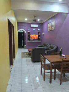 sala de estar con paredes de color púrpura, mesa y sofá en D'illahs Homestay en Alor Setar