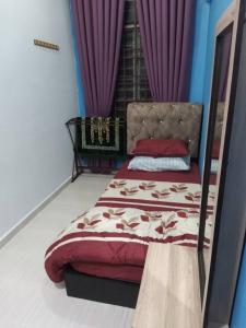 a bedroom with a bed with purple curtains at D'illahs Homestay in Alor Setar