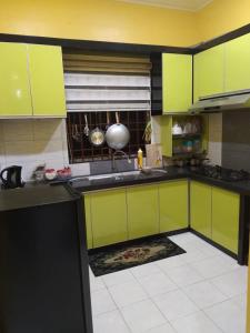 uma cozinha com armários verde lima e piso em azulejo em D'illahs Homestay em Alor Setar