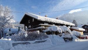 ein schneebedecktes Gebäude mit Büschen und Bäumen in der Unterkunft Hirschbachwinkel - fewo-badhindelang in Bad Hindelang