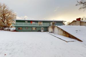 a green house in the snow with a snow covered yard at Mission Getaway in Spokane Valley