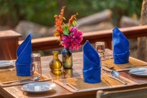 un tavolo con tovaglioli blu e un vaso di fiori di Mbali Mbali Gombe Lodge a Kasekera