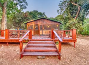 a wooden deck with a cabin in the woods at Mbali Mbali Gombe Lodge in Kasekera
