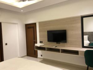 a bedroom with a tv on a wall at Hamsun Apart Hotel Clifton in Karachi